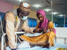 An IRC health officer screens a child at a health facility.