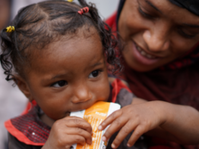 A mother holding her child as she eats.