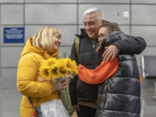 A couple welcoming a refugee with flowers.