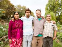 Four people pose for a picture outdoors in a garden.