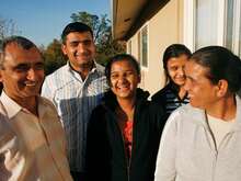 Family of five stands outside its Sacramento home, laughing together while their picture is taken.