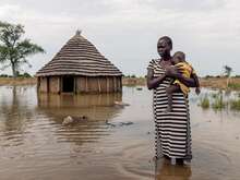 Abuk hält ihre schlafende Tochter Nyirou im Arm vor ihrem überfluteten Haus in Northern Bahr El Ghazal, Südsudan.
