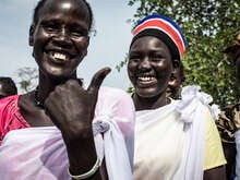 Två kvinnor i Sydsudan ler mot kameran. 