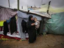 Eine Frau hält ein kleines Kind vor einem provisorischen Notun in Gaza.