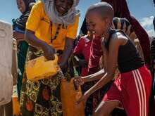 An IRC team member fills a child’s jerry can with clean water from a tap in Somalia.