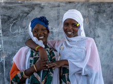 Two women in scarves looking at the camera and smiling