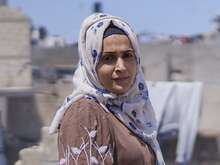 Eine Frau mit weißem Hijab und brauner Burka dreht sich um und schaut in die Kamera.