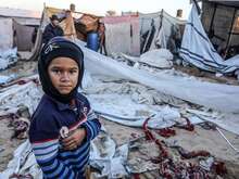 가자 지구에서 임시 거처의 잔해 앞에 서 있는 한 팔레스타인 소년.