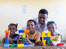 Photo of an IRC teacher demonstrating a lesson to students with LEGO blocks.