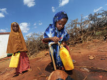 Two girls fill water jugs at an IRC-installed tap in Galkayo, Somalia 