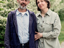 A man and woman stand next to one another and smile 