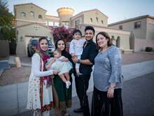 Resettled family stands in front of their home in the United States