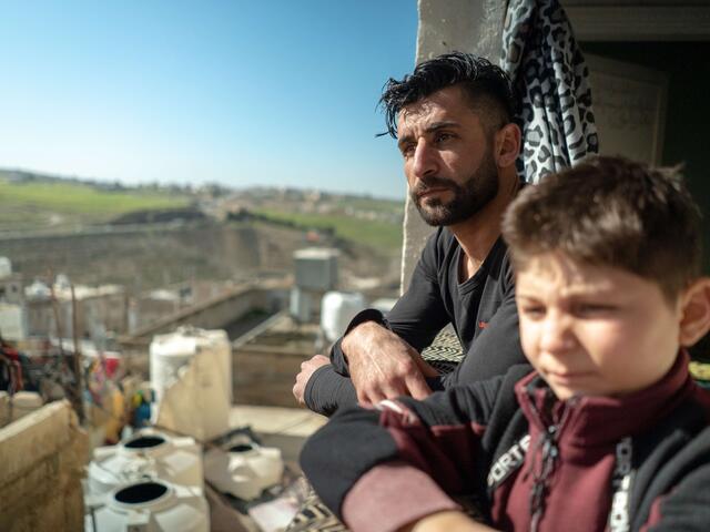 Abdessalam and his father looking from a balcony across a city