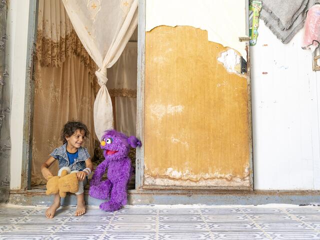 A young girl and a puppet sitting on a stair