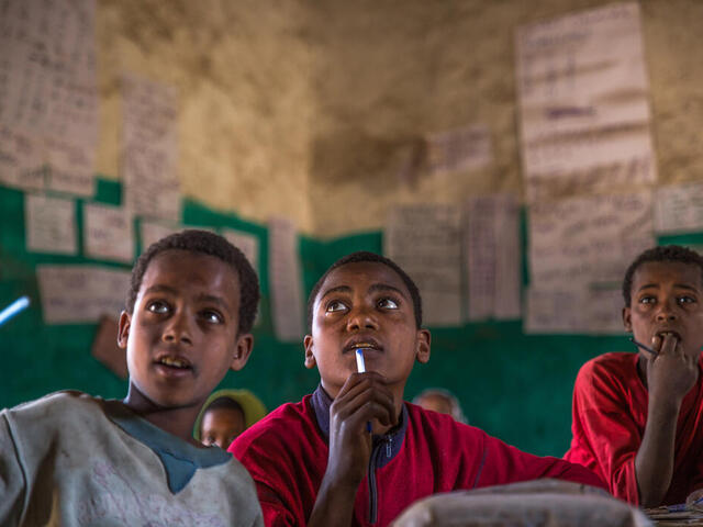 Drei Jungs schauen in einem Klassenzimmer auf die Tafel.
