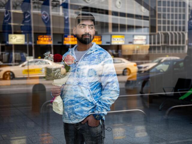 Mehdi am Flughafen hinter einer Scheibe.