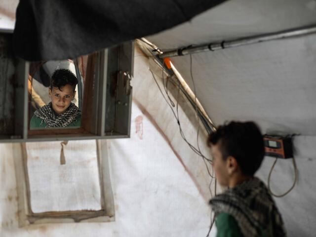 Der zehnjährige Omar sieht in den Spiegel in einem Zelt.