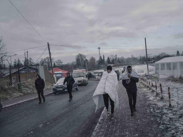 Refugees wrapped in blankets arrive at Medyka border crossing point, Poland