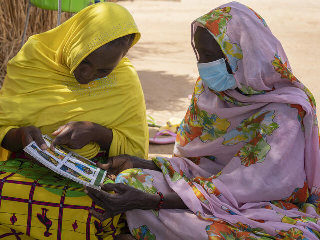 Fantaou Mallam Kiari (20) und eine andere Frau in Diffa, Niger, lesen eine IRC-Broschüre über die Prävention von Mangelernährung von Kindern. Mütter wie Fantaou erhalten von IRC Bargeldhilfe sowie wirtschaftliche Schulungen, damit sie ihre Familien unterstützen können.