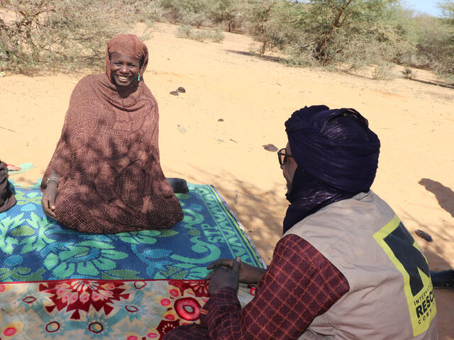 Lalla and IRC staff member sit on the floor, Lalla smiles at the staff member