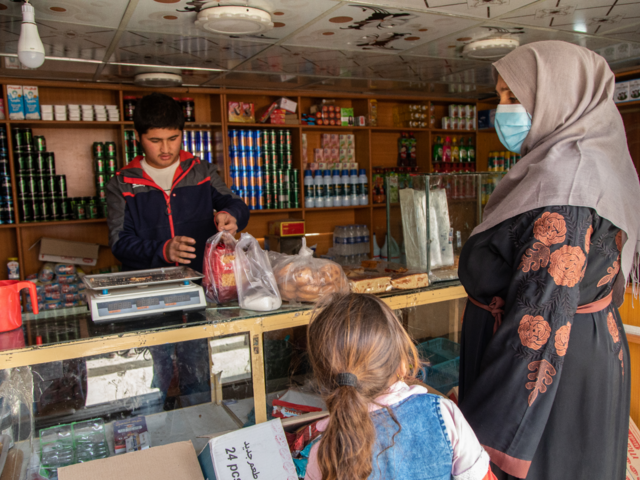 Noor* takes her daughter to the local market to purchase food for her and her children using the emergency cash assistance provided to her by the International Rescue Committee.