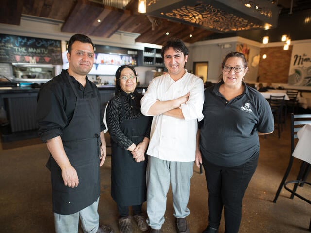 Photo of Afghan refugee and chef Noori standing with his colleagues at his restaurant in the USA.