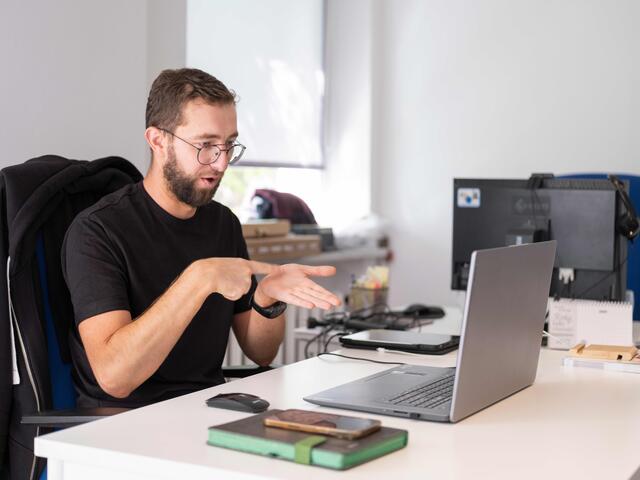 Oleksii looks at a laptop while interpreting.