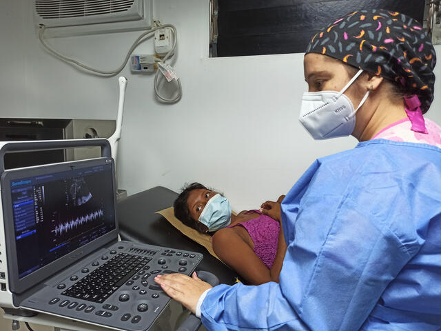 Daisy, a Venezualan woman, looks at the screen as a tech reviews her sonogram at a prenatal checkup 