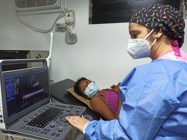 Daisy, a Venezuelan, watches the screen as a technician reviews her ultrasound during a prenatal exam