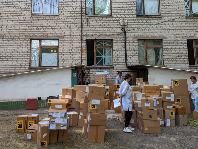 IRC staff and hospital staff are moving many IRC boxes full of helpful supplies.