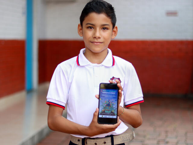 Yofrayner holds up his mobile phone, showing his access to Play Well.