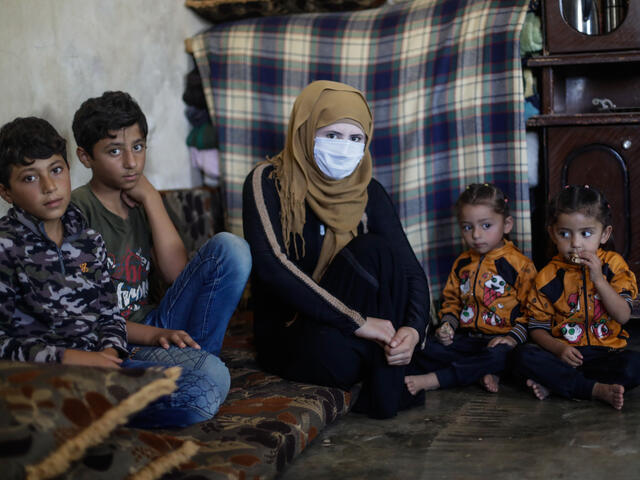 A Syrian mother sits with her 5 children on a small mattress