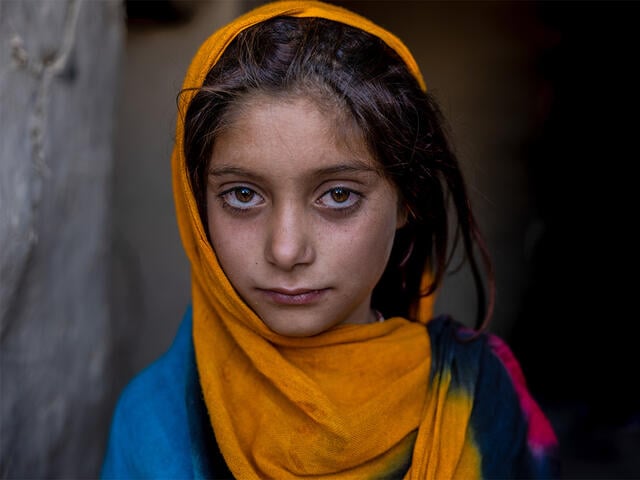 A girl poses for a portrait, staring solemnly into the camera.