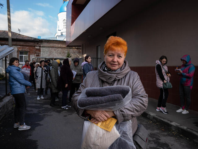 An older Ukrainian woman holding a blanket distributed by the IRC