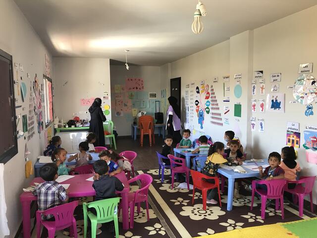 Preschool children and their teachers in a classroom in Lebanon fecorated with Sesame Street charaters. 