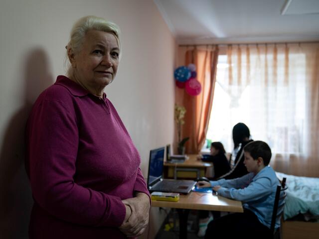 A woman, Valentina, in the forefront, with three people sitting at desks behind her