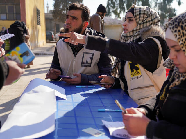 IRC staff sat at a table running cash assistance services for people affected by the earthquake.