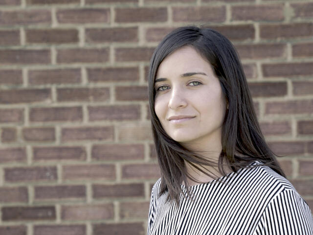 Waad Al-Kateab, Syrian activist and journalist, faces the camera against a brick wall.