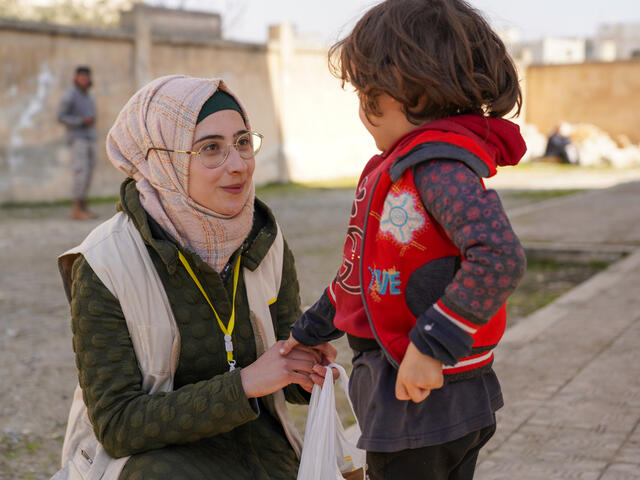 A young boy in northwest Syria receives food items from an IRC emergency response worker.