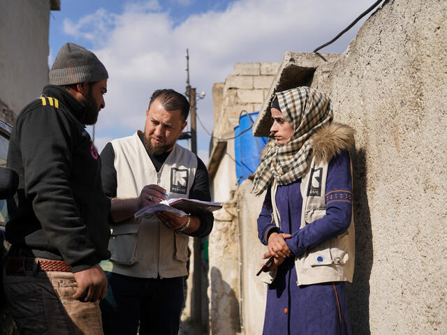 An IRC frontline worker talking to two Syrians outside
