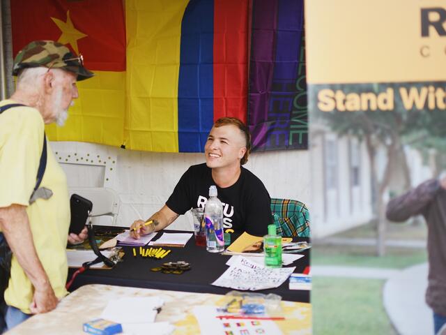 Dax, they/them, tabling for the IRC at a community event in Tucson