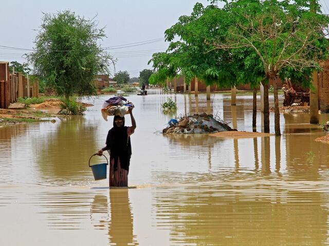 A woman wades through flood water in Managil city.