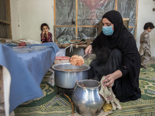 Mariam finalizes the dish presented during her cooking class and prepares to serve it to the participants: Afghan women and children. 