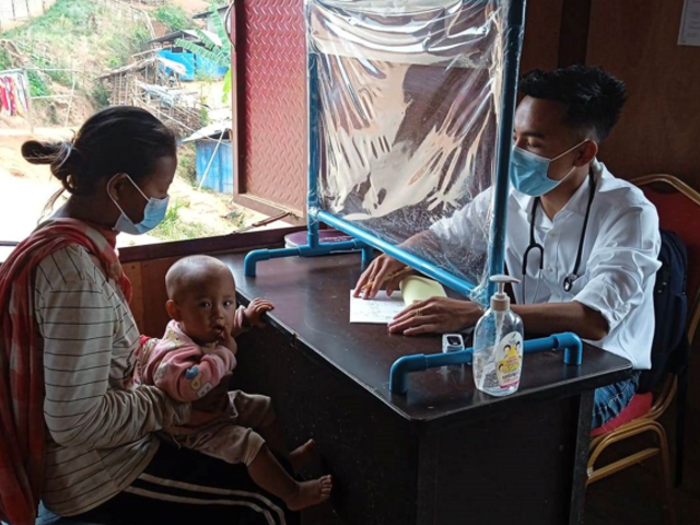 At the clinic, a medical doctor gives a consultation to a displaced mother and her child. 