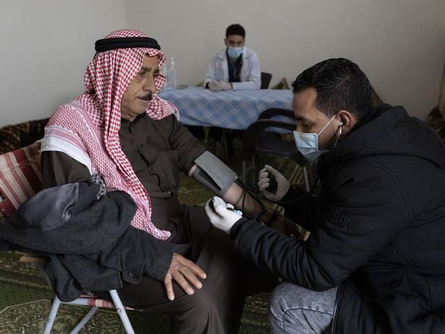 An IRC health worker measures Saif's blood pressure. Saif*, 58, is a cholera patient.
