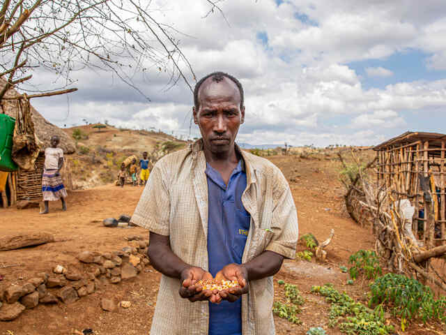 En bonde håller i frön och står mitt i hans by. 