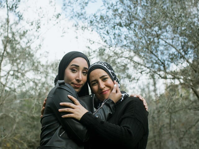 Nour with her mother, Nidal Al-Hajjar, stand hugging and facing the camera.