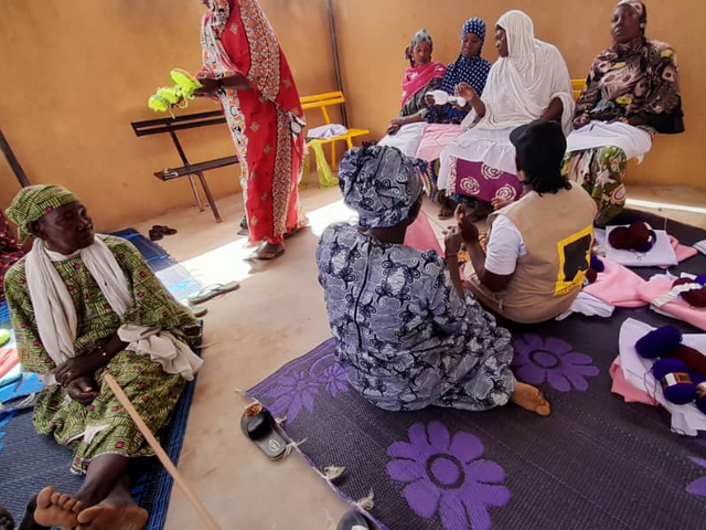 Malian women and girls exchange tips during an IRC knitting workshop funded by the European Union.
