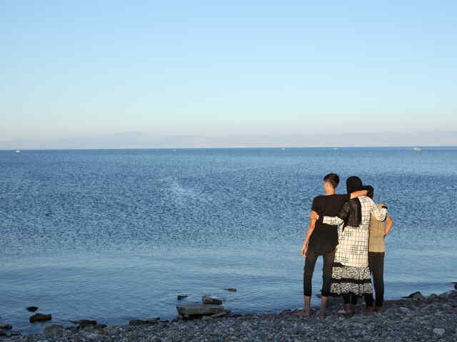 En mamma och hennes två söner tittar ut över Medelhavet i Grekland. 