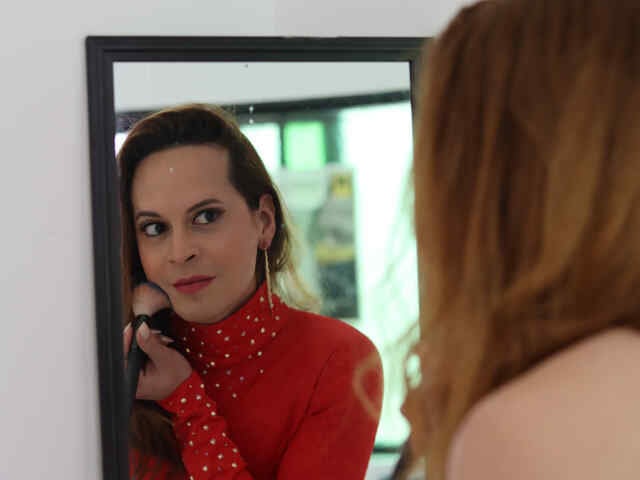 Candy looks at herself in the mirror, holding a makeup brush.